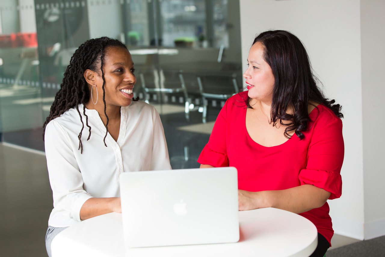 Two women at desk with laptop.