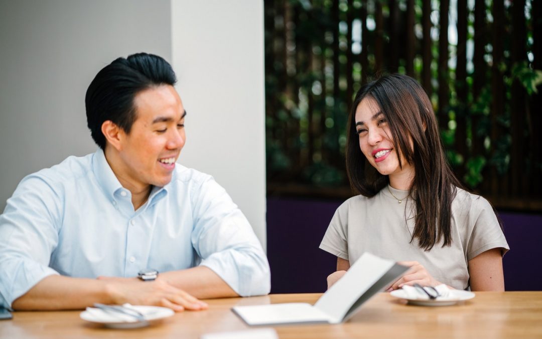 Man and woman at table with notebook.