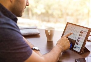 Man scrolling through Android tablet on desk