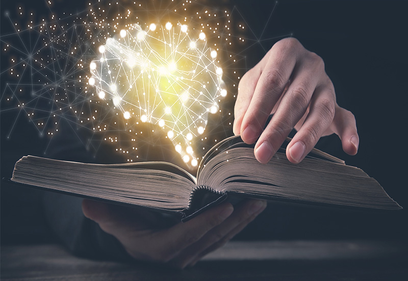 Artificial intelligence in the literature landscape – picture of glowing dots in the shape of a brain, floating above a book
