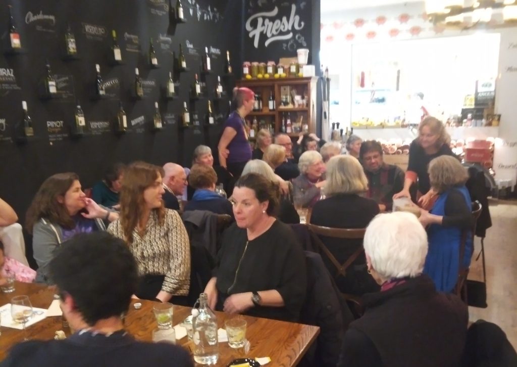 A large group of people sit at two long tables in a restaurant.