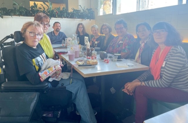 A group of people sit around a long table at a restaurant. 