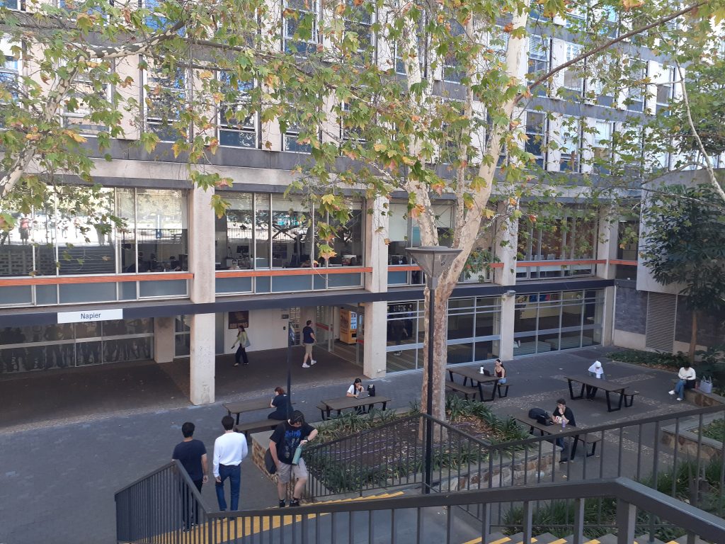 A level-access courtyard that can be accessed from the adjacent building via automatic sliding doors. The building sign reads 