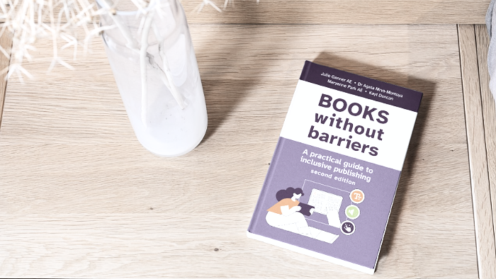 Cover for Books without barriers second edition, with a graphic of a girl who is reading a tablet. She sits on the ground with one knee raised and her elbow resting on the knee. To the right is a second drawing of her hand pointing at the text she is reading, and the symbols for text, audio and braille.